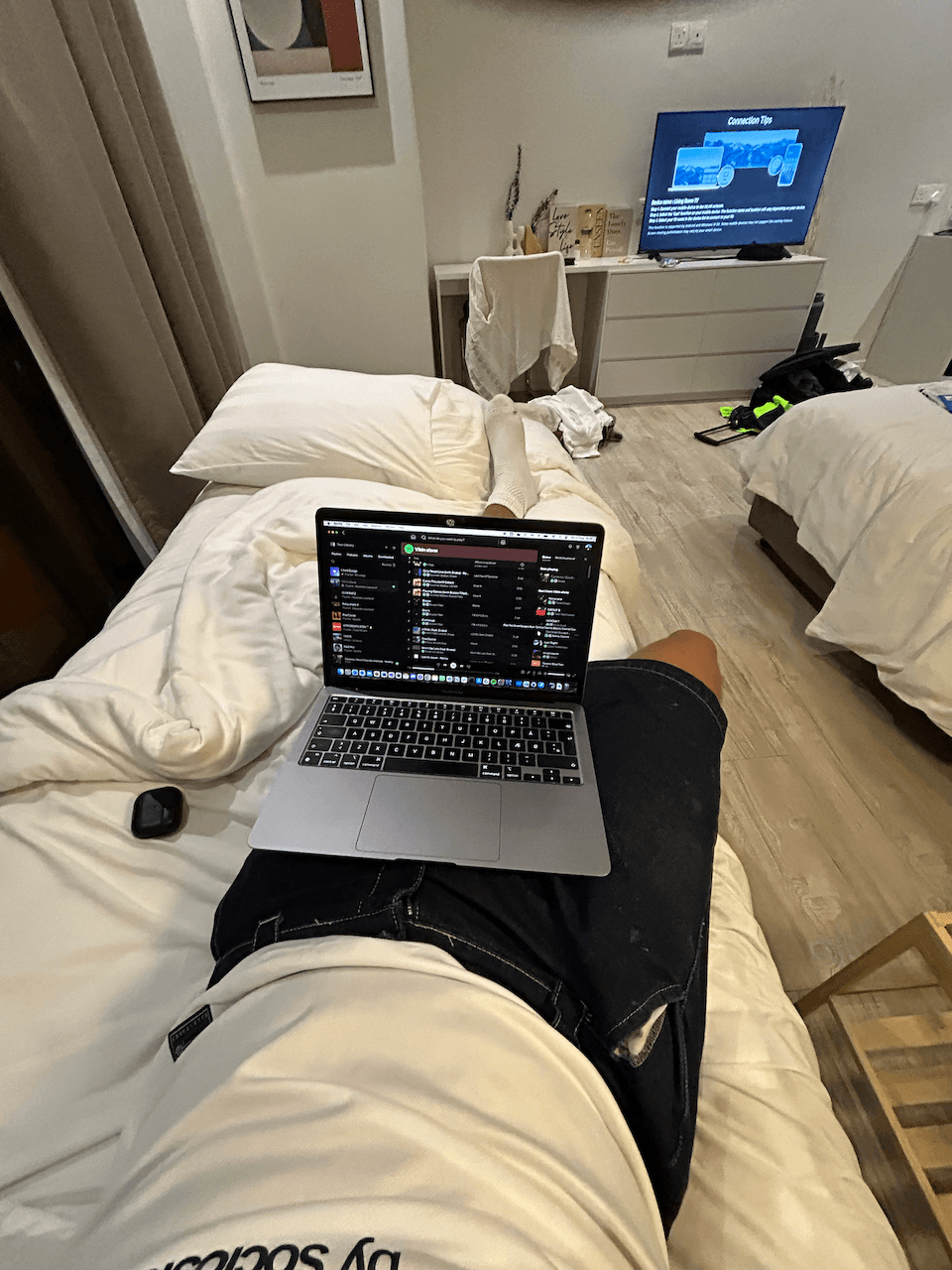 Person sitting on a bed with a laptop planning a trip